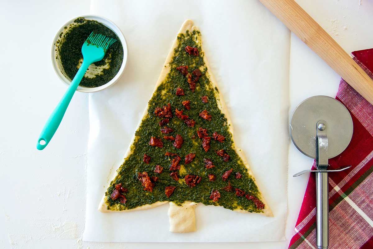 Dough topped with pesto and sun-dried tomatoes